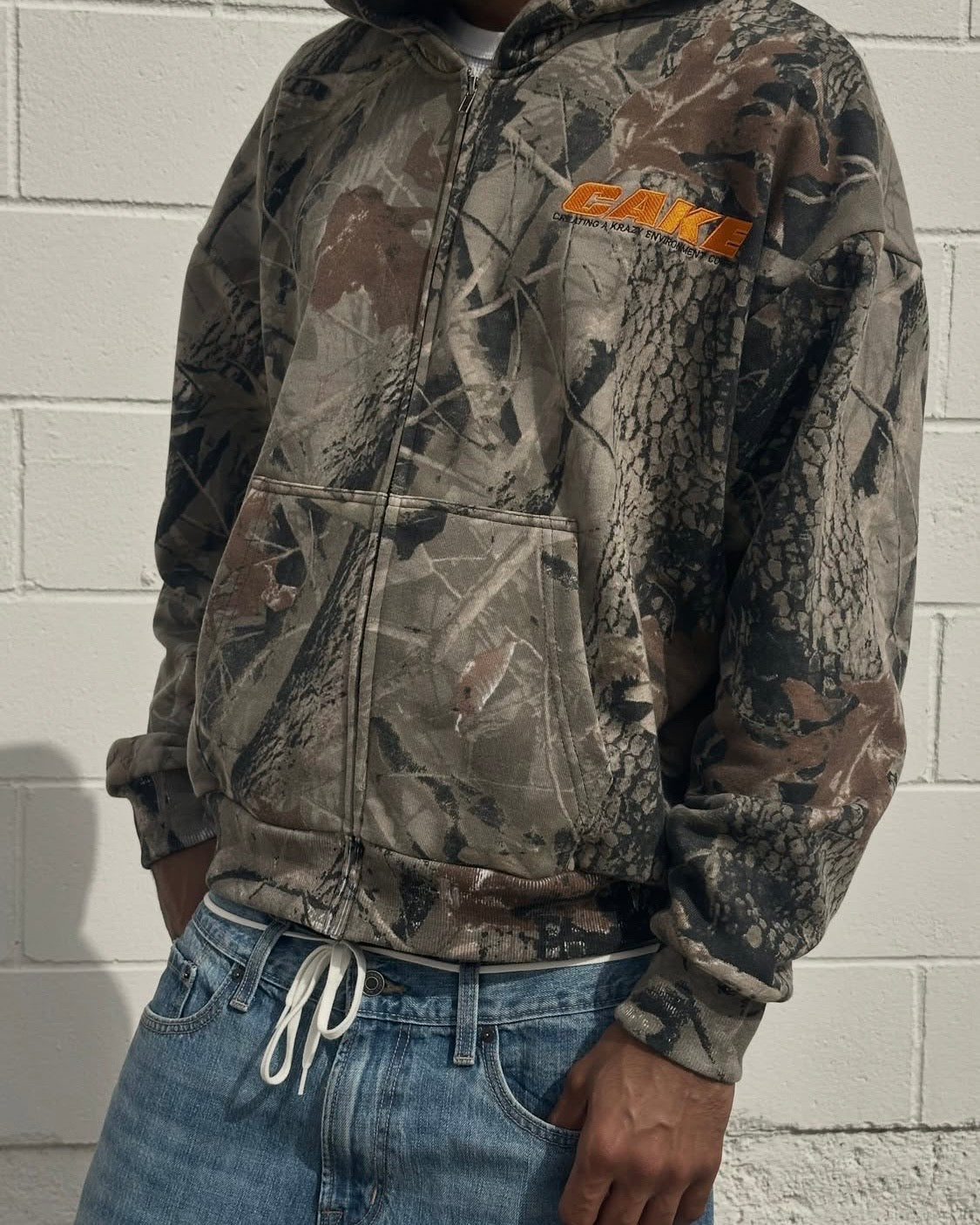 forest camo hoodie close-up with orange CAKE chest logo